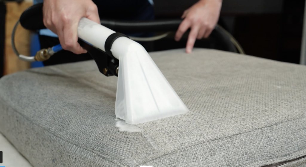 Deep cleaning a couch cushion with an upholstery extractor