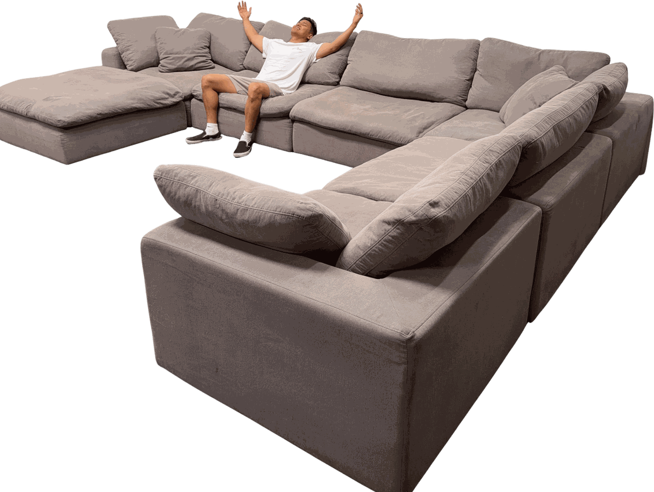 Isaac celebrating arms-up on a huge grey sectional from SD Couch